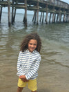 curly haired boy standing in the sea wearing lemon short Blue white stripped strips Terry Zip up Hoddie  
by Henry.