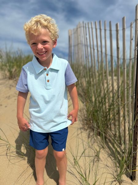 Blonde Boy in the sand Blue shorts, and a Blue body royal Blue sleeves ,polo, short Sleeved ,Sleeves ..by Henry.