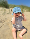 Indigo, , denim, bucket, hat, grey, onesie, button, buttons, pocket, little, baby, sitting, in, the, sand, holding, his, hat, summer, henry.