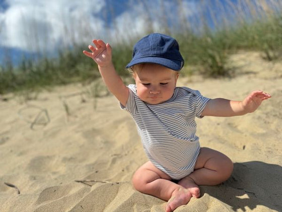 baby, sitting, in, the, sand, wearing, navy, woven, cap, stripe, stripes, striped, onesie, summer, henry.