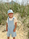 Boy, wearing, Stonewash  denim, Buckled, ,overalls, beige, tee, matching, stonewash, denim, bucket, hat, standing, on, sand, in, the, long, grass, henry.