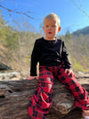 Red & black plaid, lounge wear, kids, cotton, black, kids clothing,  polyester, grey drawstrings, small blonde haired boy, black pique BRADEN slub henley top, sitting on tree branch, sunny, woodlands