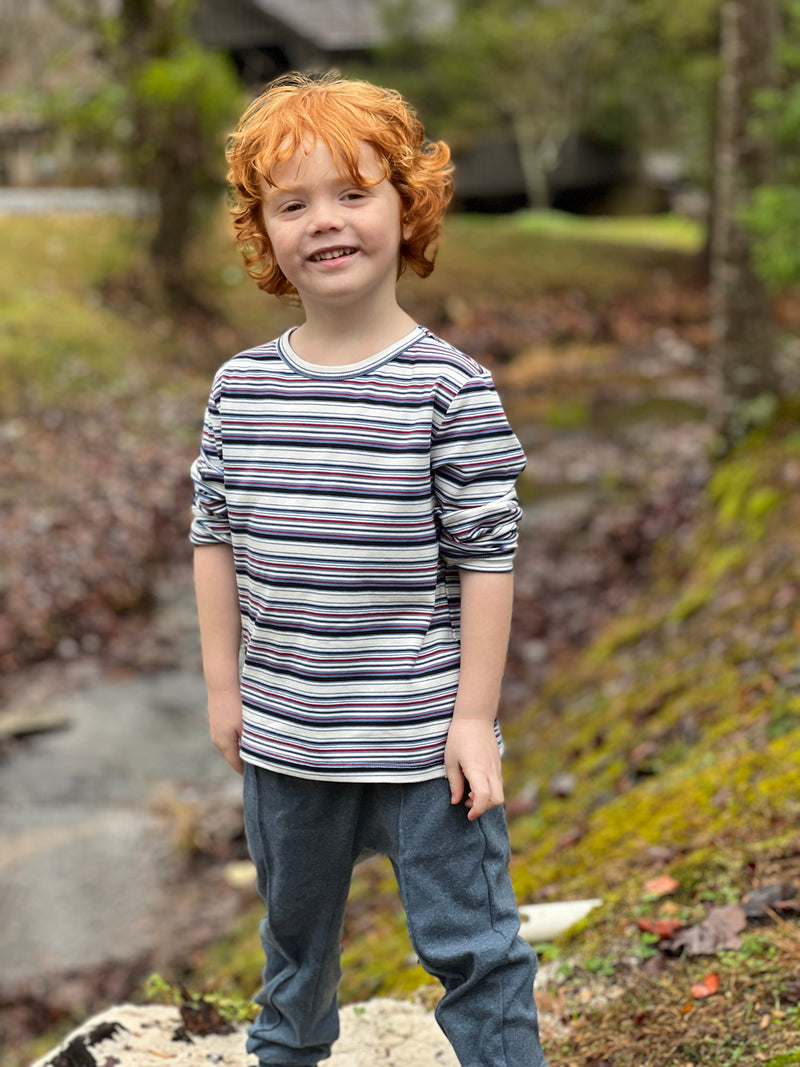 blue jog pants, white drawstrings, cuffed ankles, flexible waistband,cotton, polyester, spandex, little boy, ginger hair, navy/ light blue/ white striped tee, woodlands, small stream. mud, grass, leaves, bright day