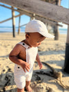 Beige, woven, cap, beige, buck[ed, overalls, little, babby, boy, under, the, pier, in, the, sand, summer, henry.