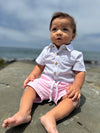 Baby sitting on a rocky beach with ocean in the background