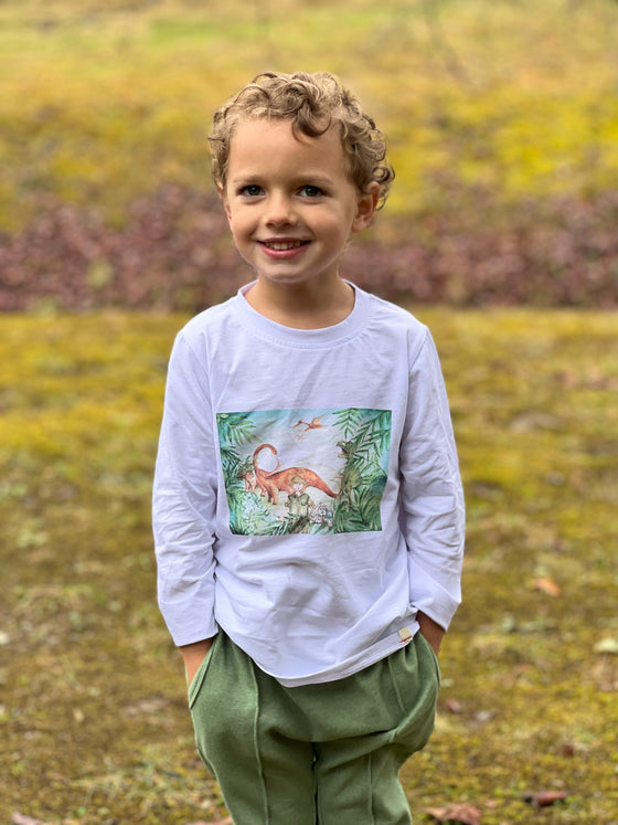 little boy, blonde curly hair, wearing white dino scene tee, khaki twill pants, outside in garden