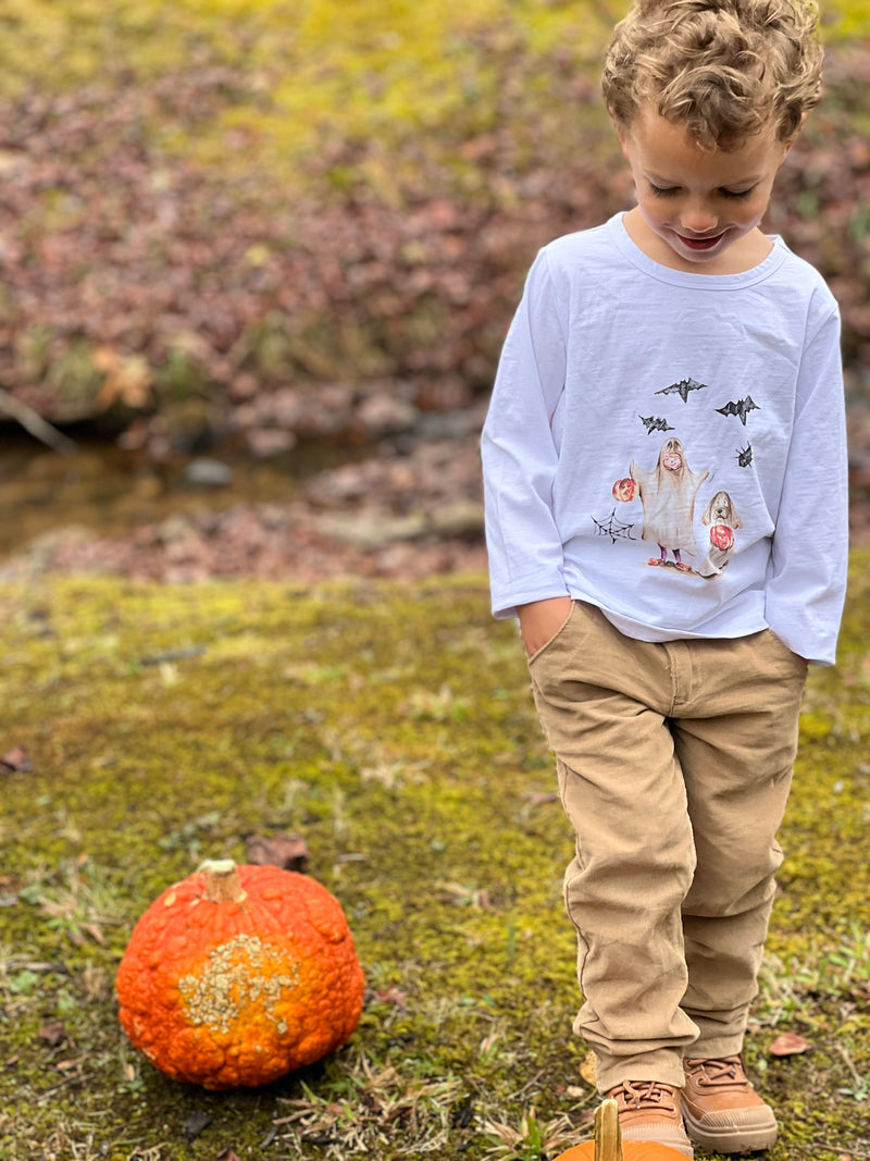 little boy, wearing white Cherokee raglan printed Henry ghost tee, stone twill pants, outside in the garden, next to a pumpkin