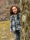 Curly, hair boy standing next to a tree, Black/White, Lumberjacket, Grey Henley, Charcoal, Pants, Warm,  Smart, Autumn, Winter, casual.