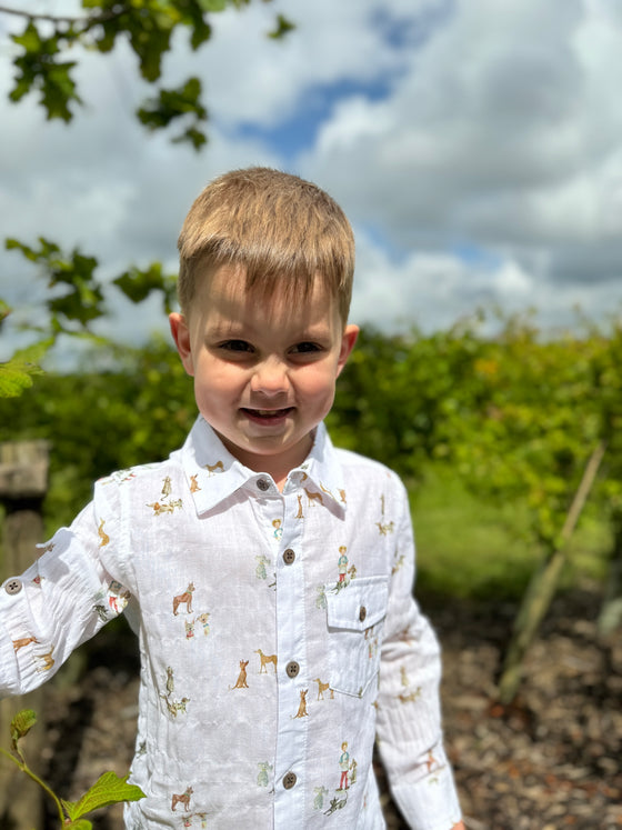 A fair-haired boy stands next to a busy white shirt with an all-over Henry print, featuring buttons and long sleeves, sleeved, sleeve, for a smart look.