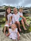 blonde hair boy wearing our candy stripe woven shirt and turquoise gauze shorts at the beach.