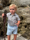 Child holding a sea weed in a Woven Multi/Blue, Beige, stripe onesie, pale blue shorts.