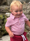 Child wearing a Red striped Woven Onesie and red shorts standing on a rocky surface.