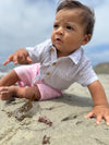 Baby crawling on the sand with a blurred beach background