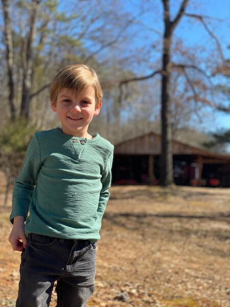 green, slub, top, button, buttons,             charcoal, jeans, casual, cool,  spring,        autumn, henry, long sleeved, sleeves, sleeve, fair hair boy standing on a lawn.                         